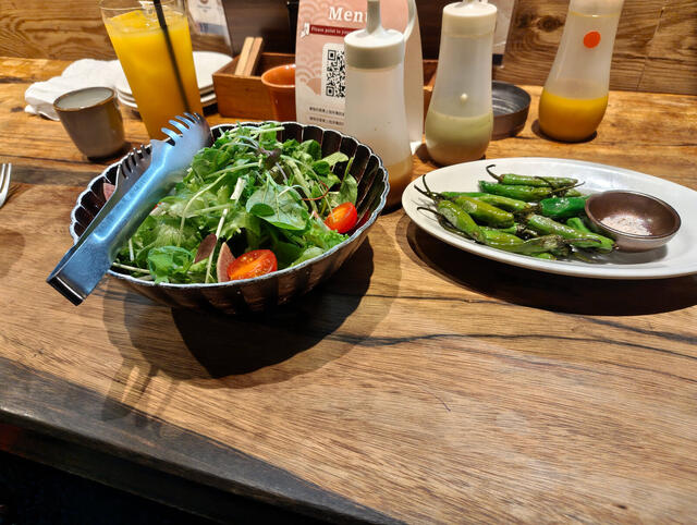 Cena en barra: ensalada verde, shishito salteados con sal, carne en plancha de hierro con papas fritas y salsas, sal y wasabi. Para tomar, jugo de naranja.