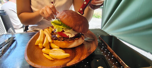 Hamburguesas en terraza con papas fritas gruesas en plato de madera; una con bacon, tomate y lechuga, y otra doble con ketchup Heinz. Almuerzo cerca de Arashiyama.